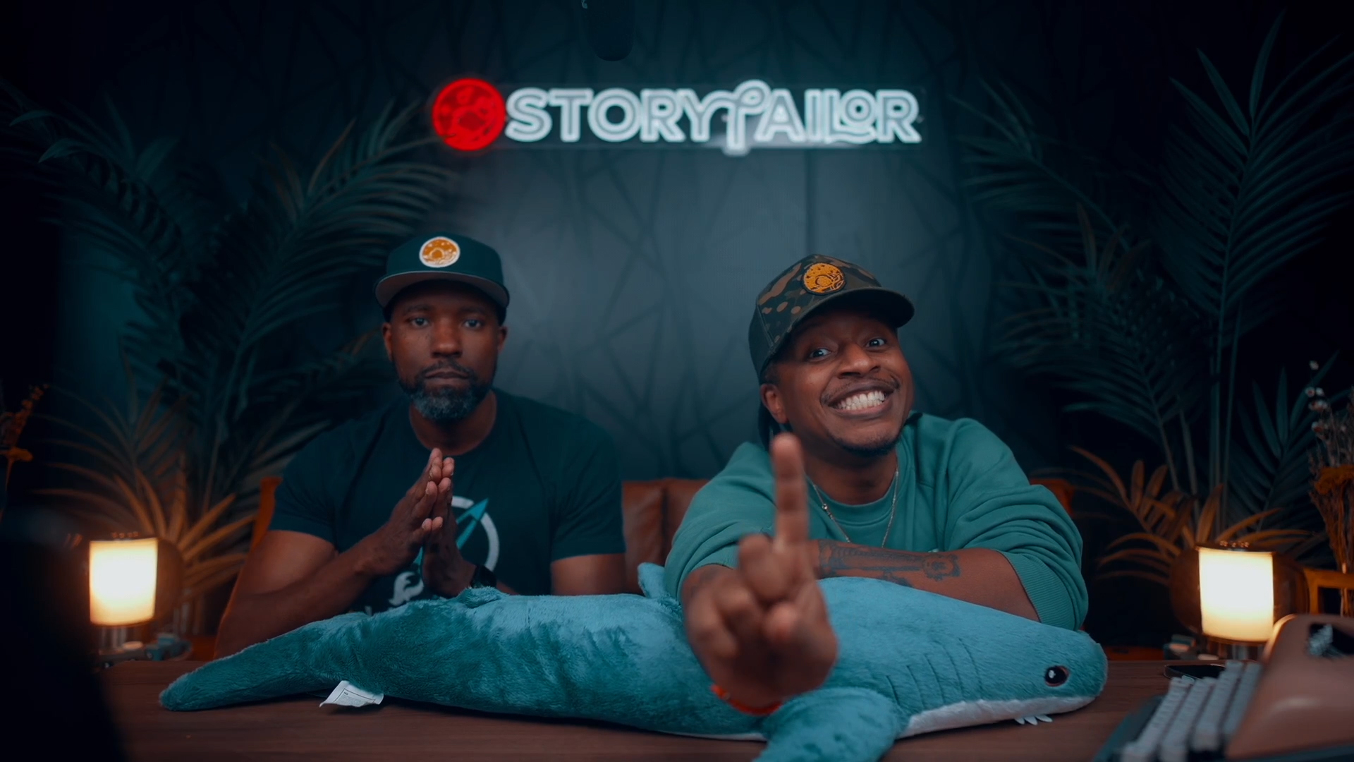 Herston, left, and JQ, right, together behind a giant plush shark beneath the Storytailor sign.
